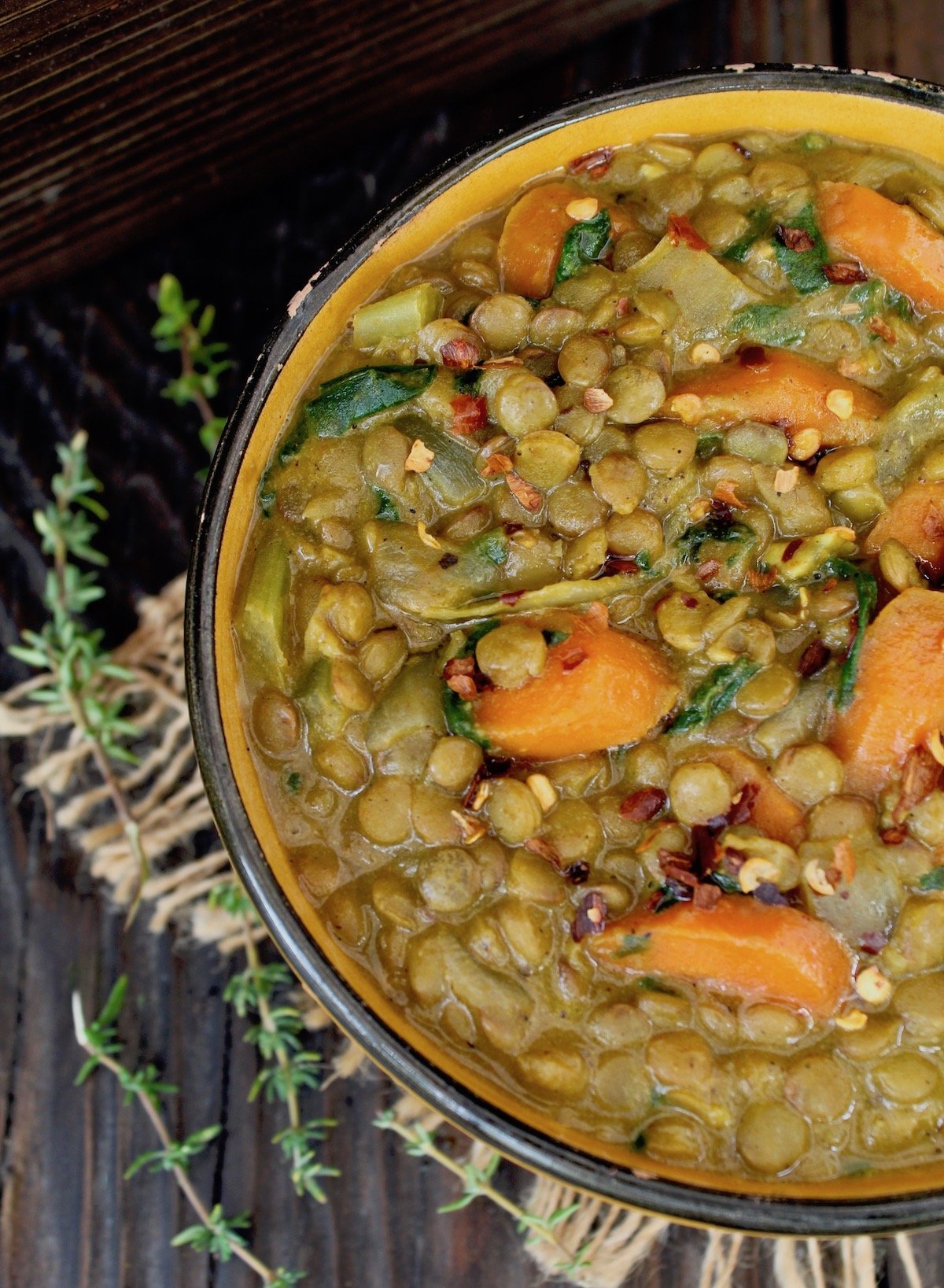 top view of curried lentil stew with carrots and fresh thyme sprigs