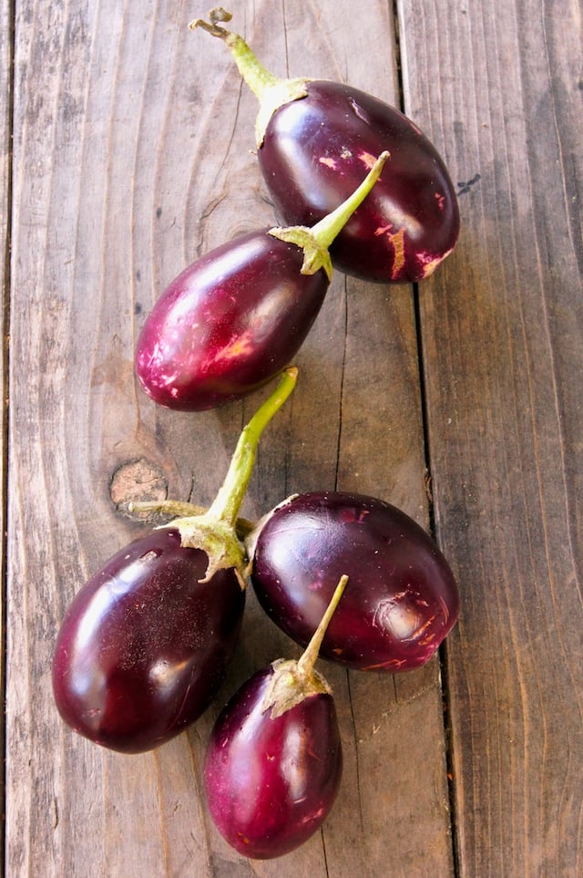 five Indian eggplants on a wooden surface
