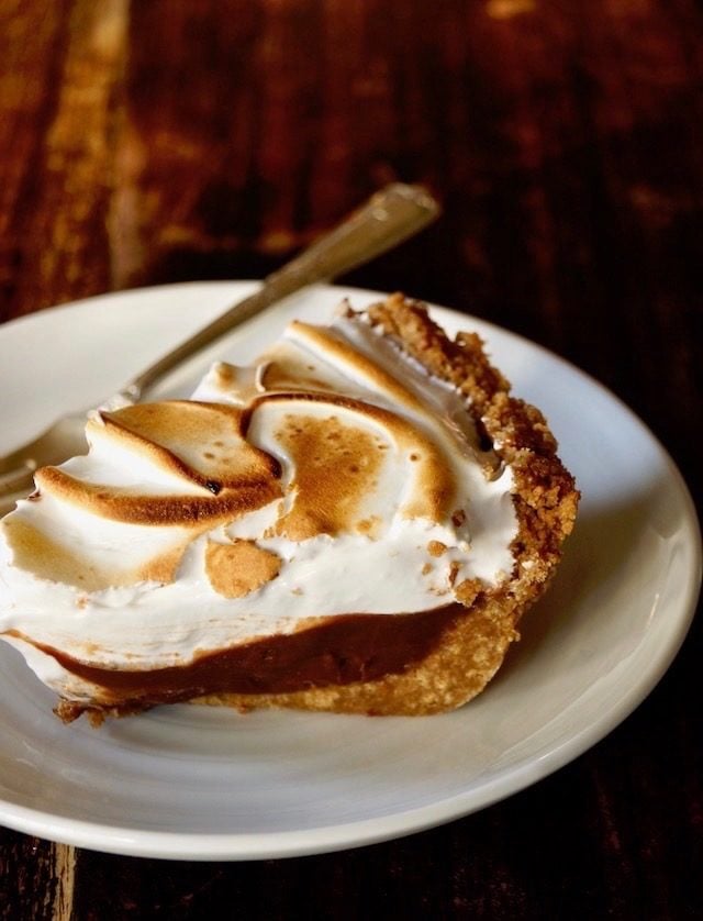 One slice of Peanut Butter Chocolate Meringue Pie on a white plate with fork