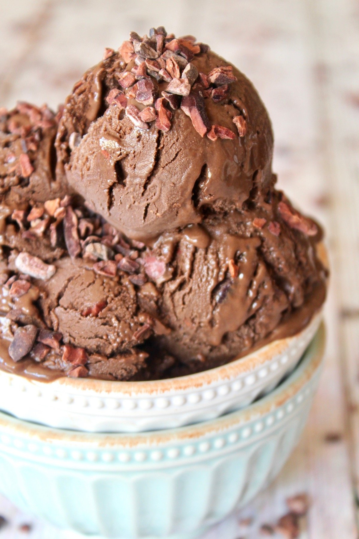 close up of chocolate gelato scoops with chocolate nibs in white bowl