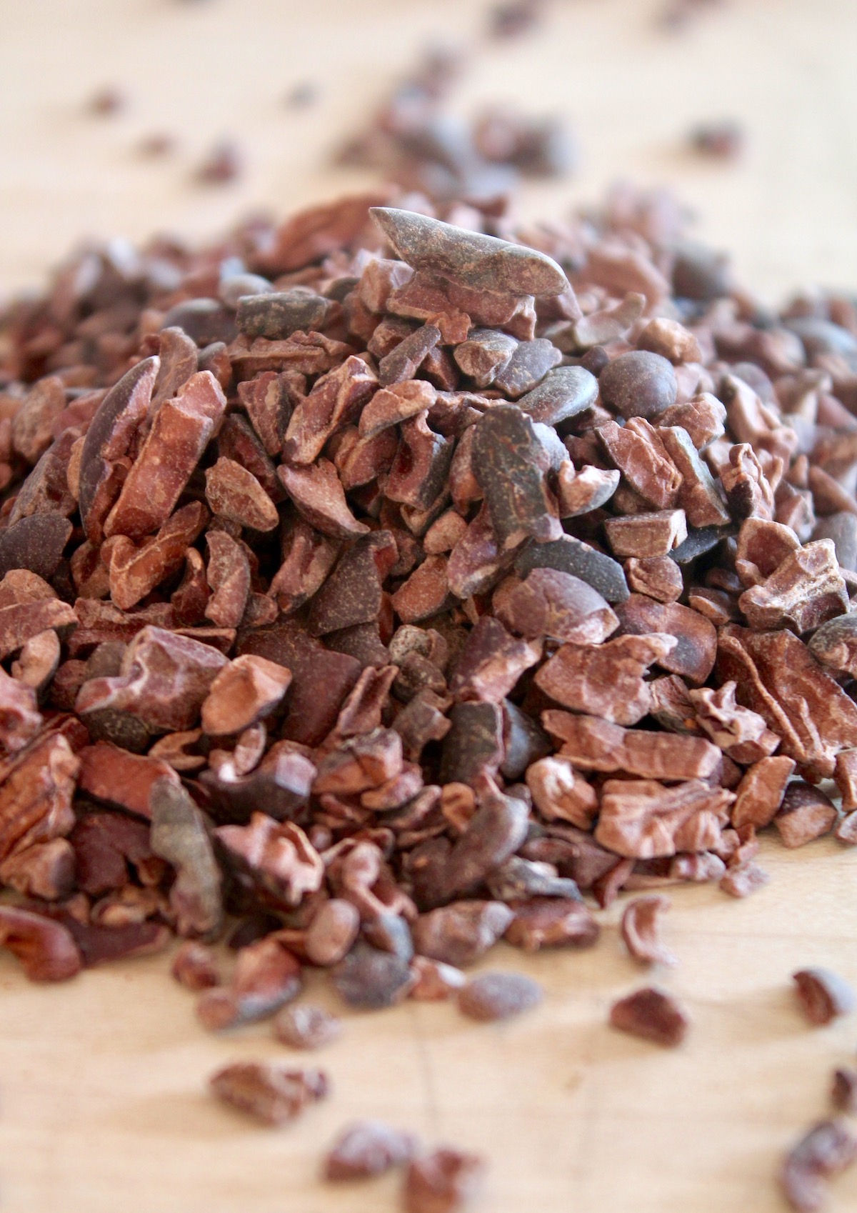 pile of cacao nibs on light wood cutting board