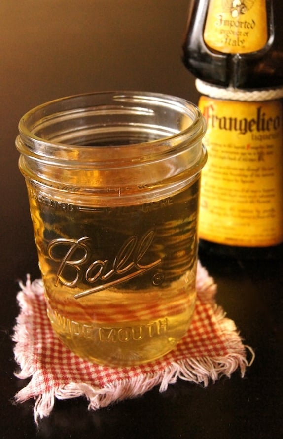 Hazelnut Simple Syrup in a Mason jar with a bottle of Frangelico behind it.