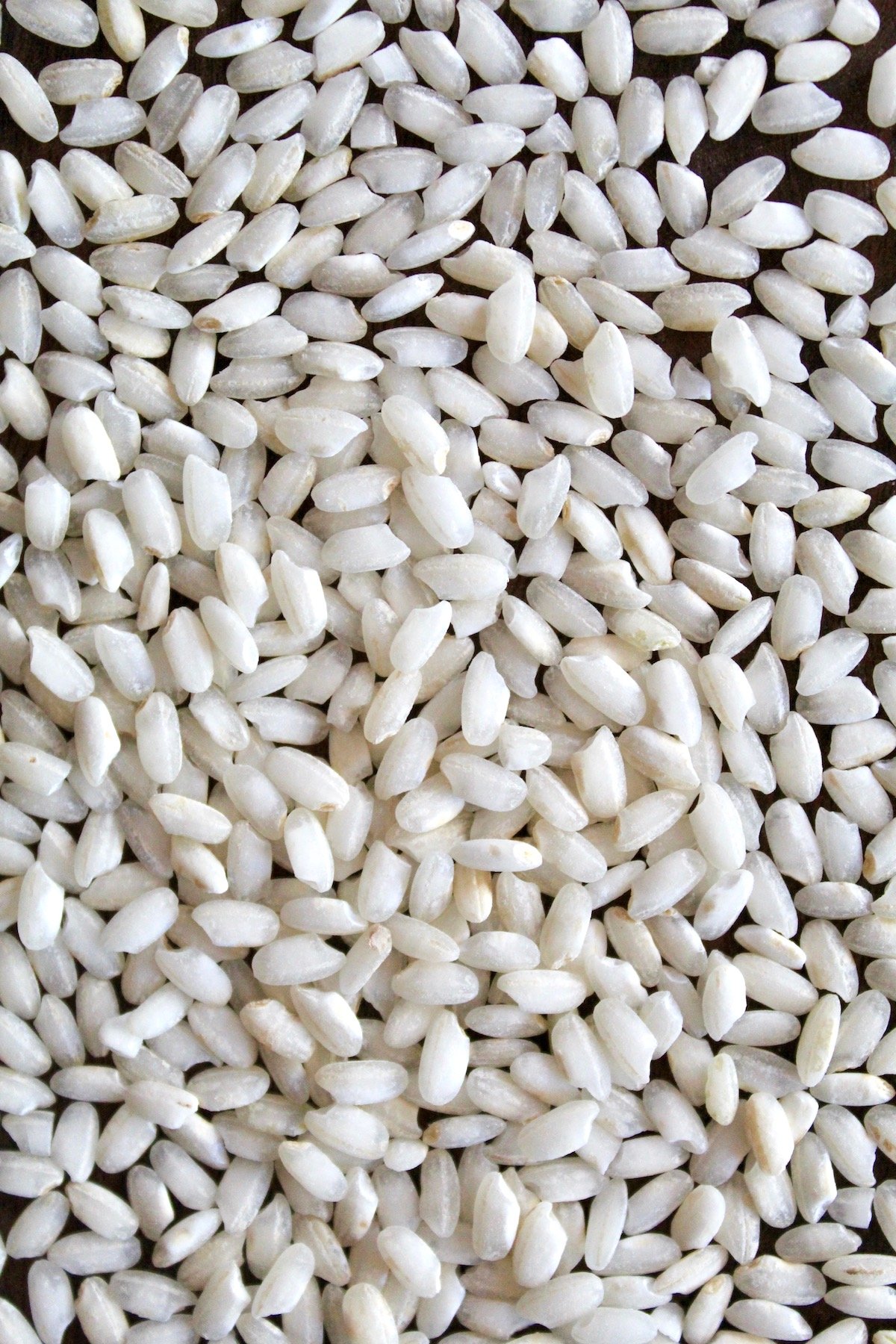Arborio rice grains on a dark table.