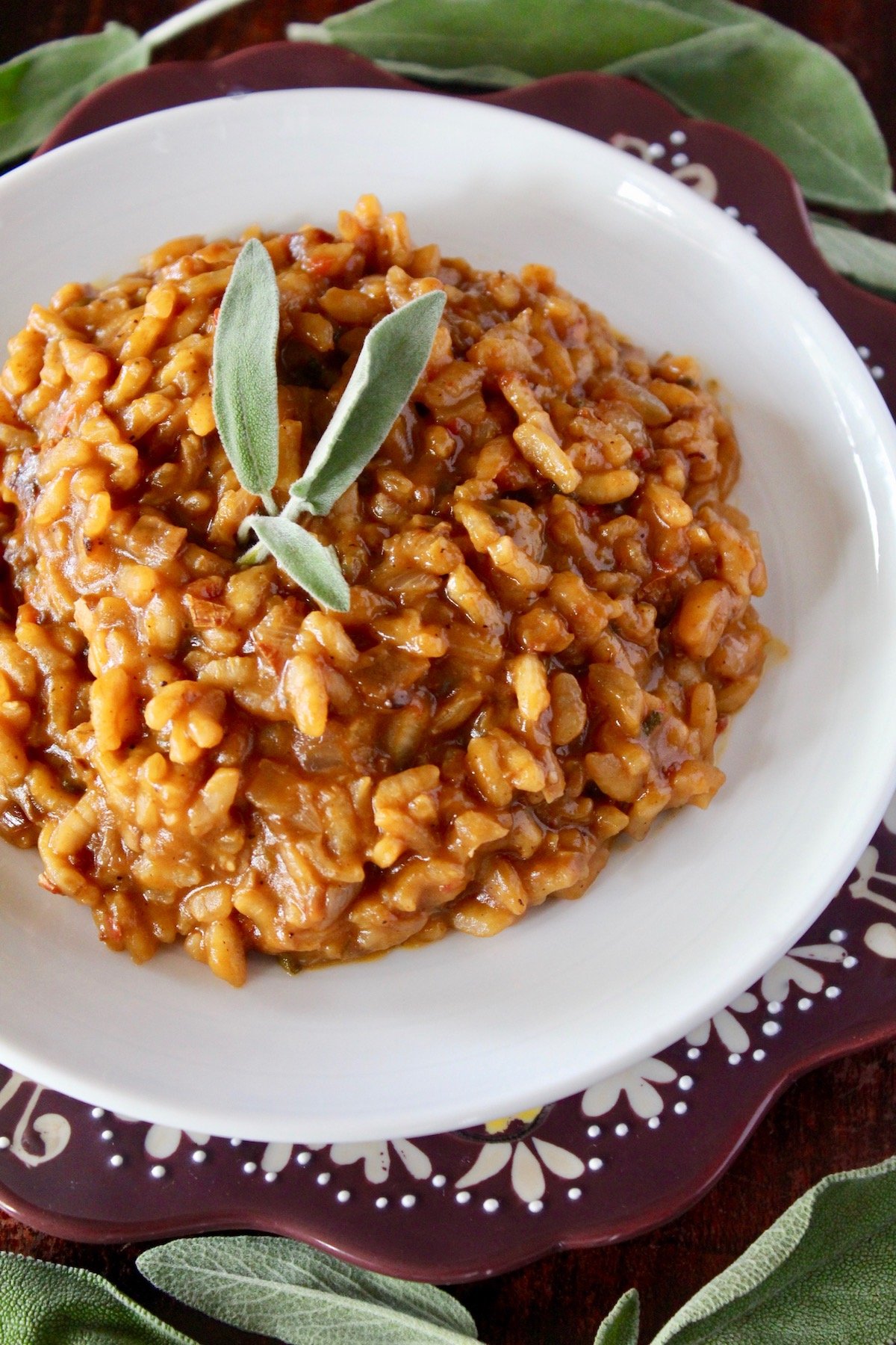 Pumpkin risotto with sage leaves on a white plate.