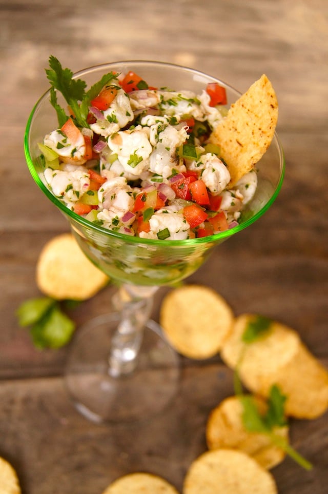 A green-tinted wine glass filled with Tomatillo Shrimp Ceviche.