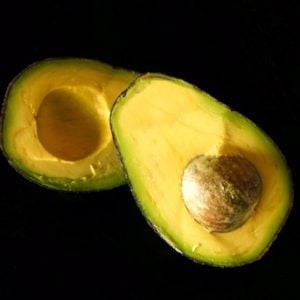 an avocado cut in half with pit still intact