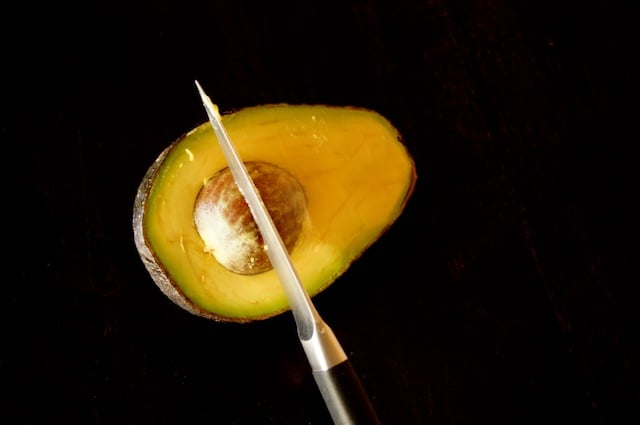 avocado half with pit being removed