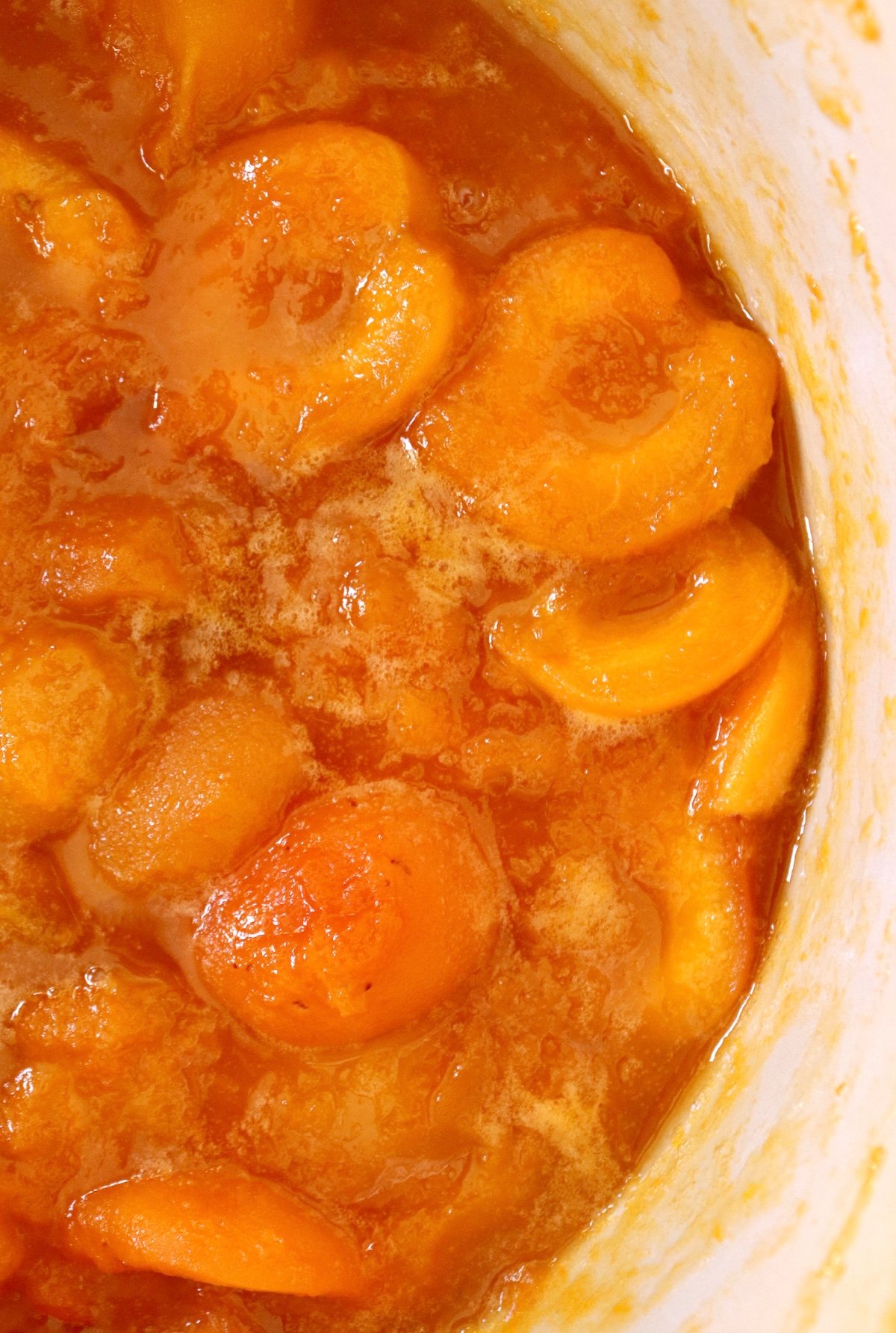 Top view of half a Dutch oven with chunky apricot preserves.