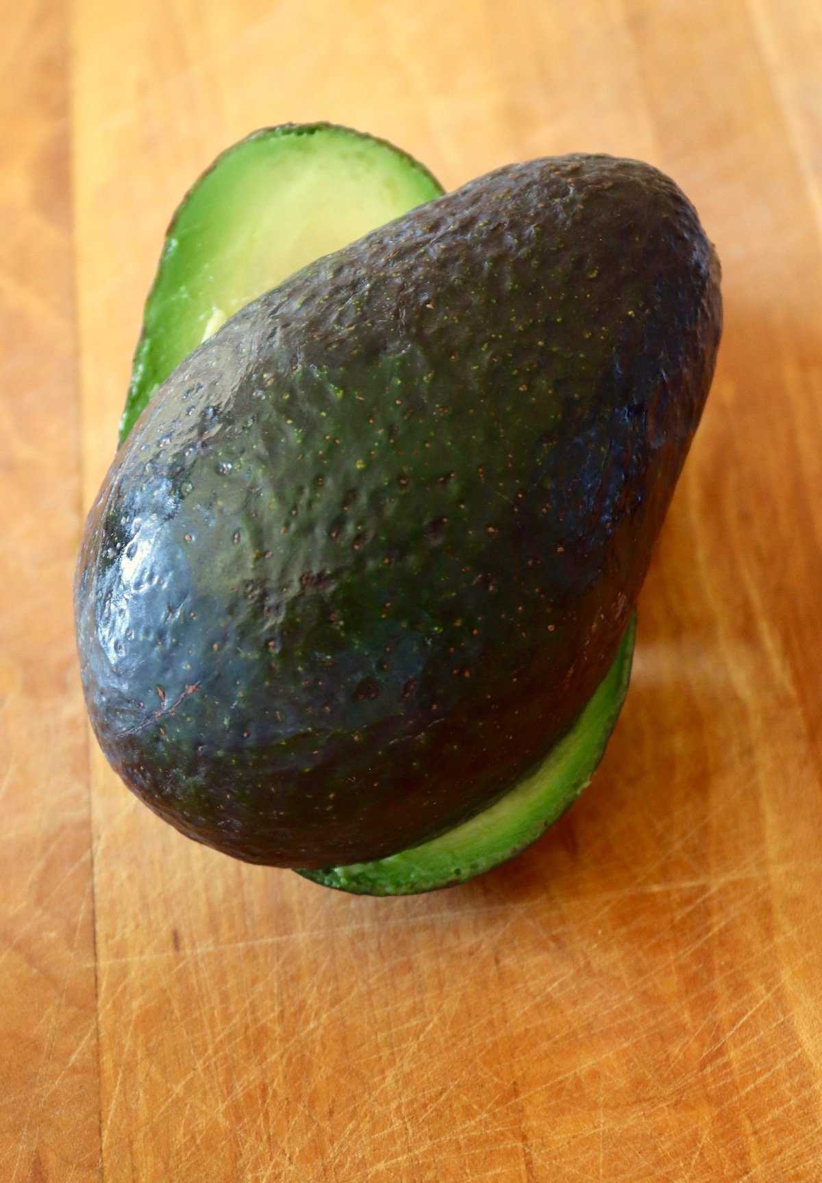 Two avocado halves slightly twisted open to show a bit of the inner green flesh.