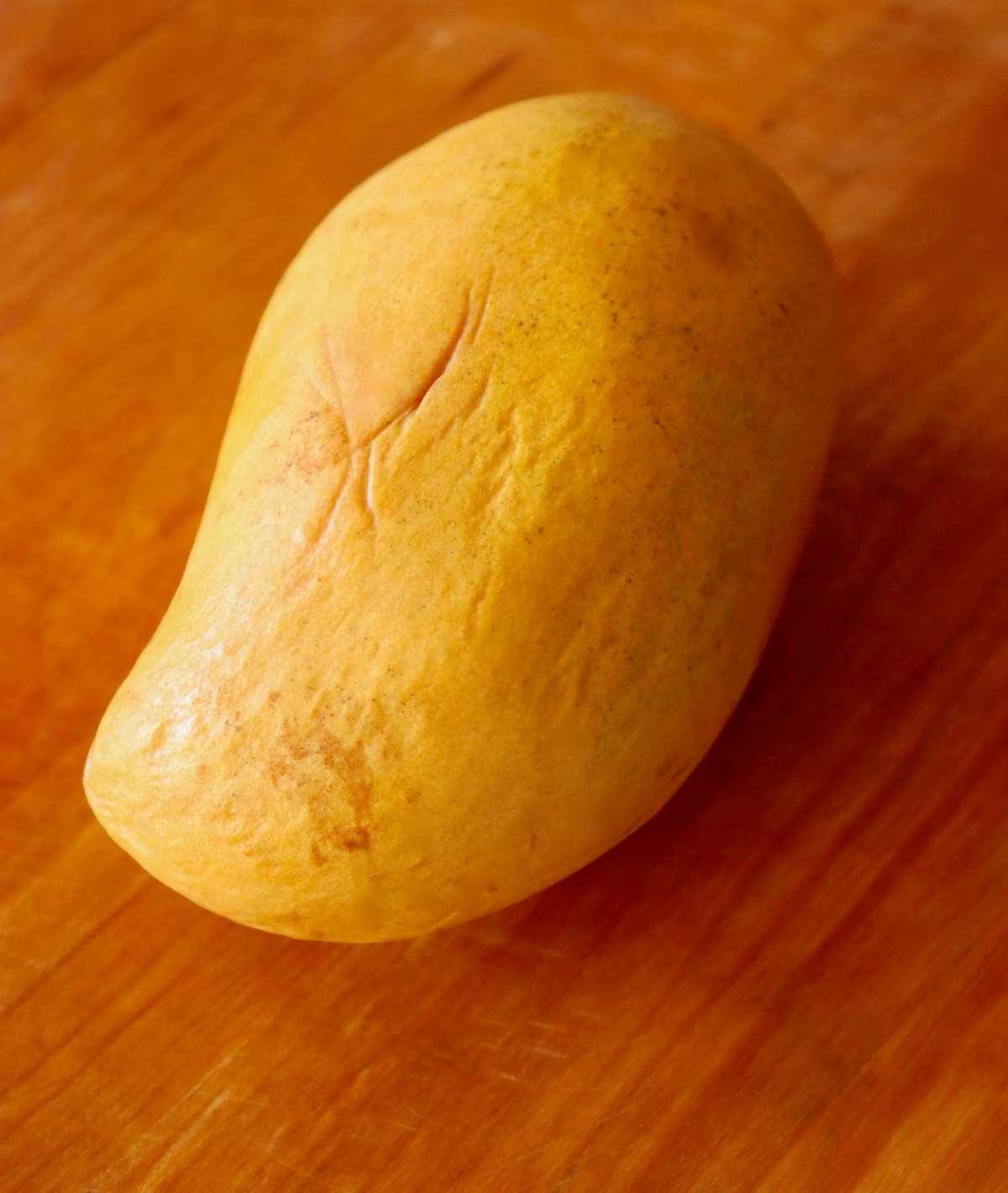 Whole Honey mango on cutting board.