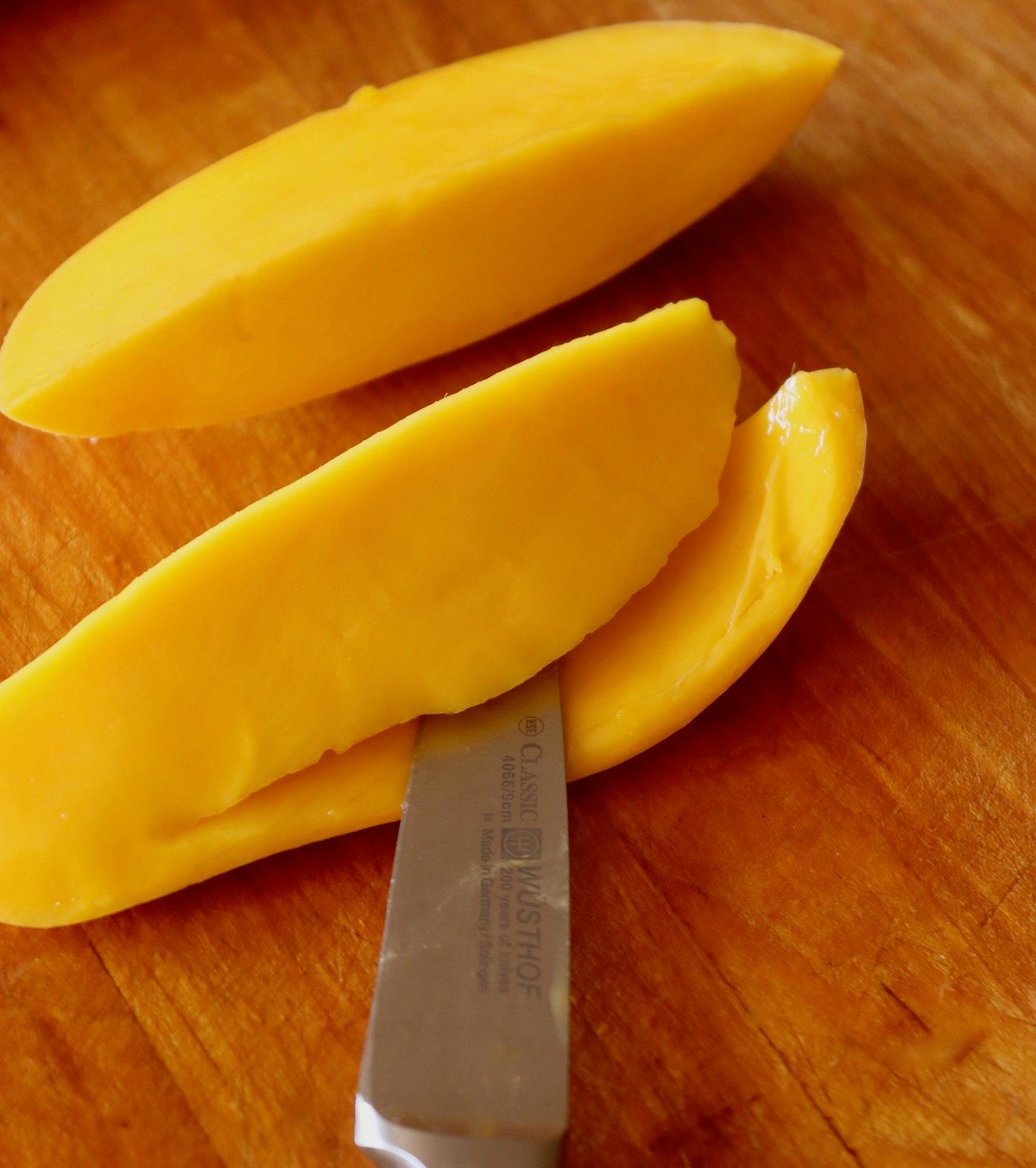 Mango quarters being sliced between the skin and flesh.