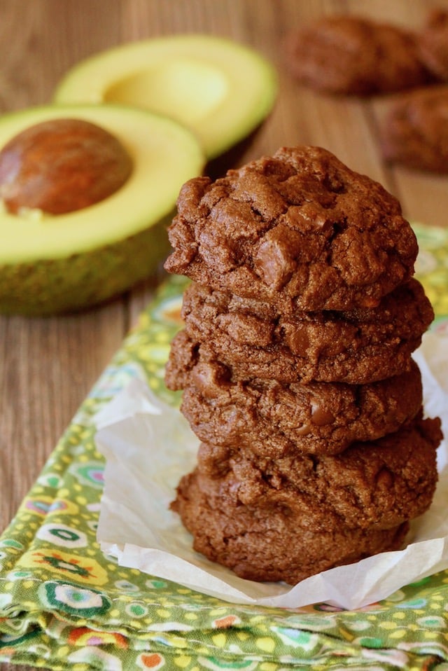Tall stack of Double Chocolate Avocado Cookies with avocado cut in half in background