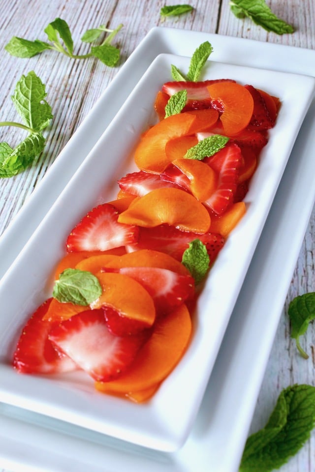 narrow white plate with sliced apricots and berries