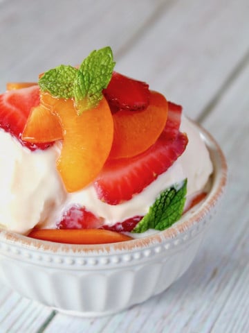 minty strawberries and spricots over vanilla ice cream in white bowl