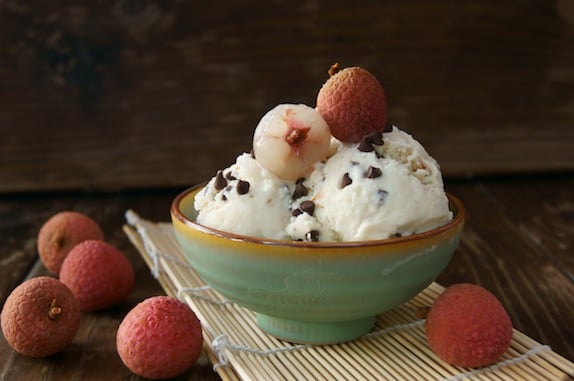 Lychee Ice Cream Recipe in a green bowl with fresh lychee on top and around it.