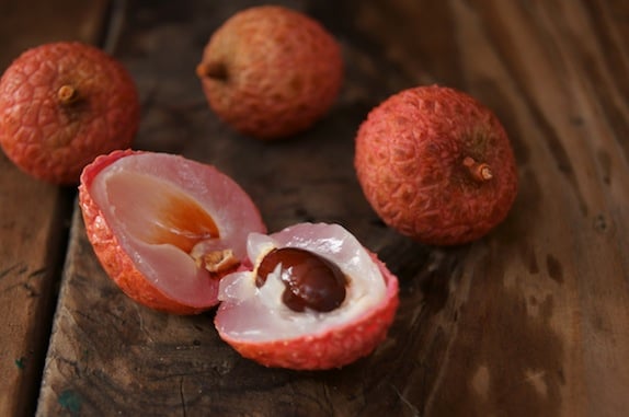 a few Lychee with one cut in half on wooden surface