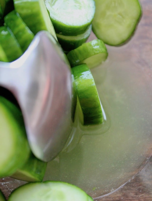 spoon with cucumber slices in glass bowl