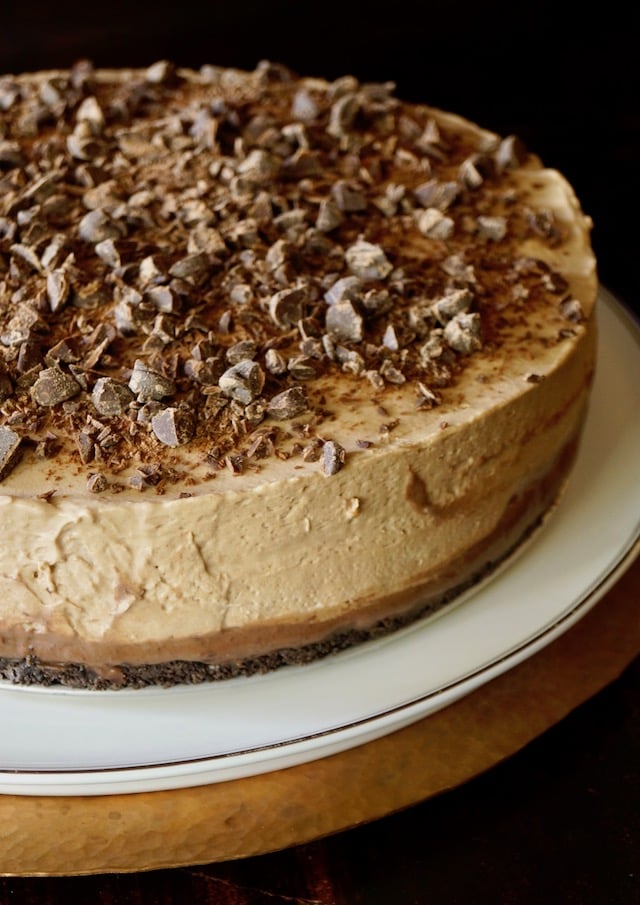 No-Bake Espresso Cheesecake with Ganache on a white cake stand.