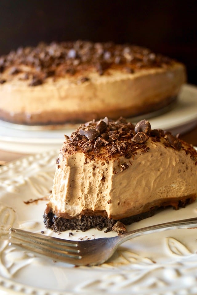 Slice of No-Bake Espresso Cheesecake with Ganache with one bite missing on cream plate