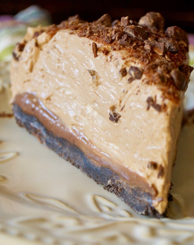 One big slice of No-Bake Espresso Cheesecake with Ganache on a cream plate.