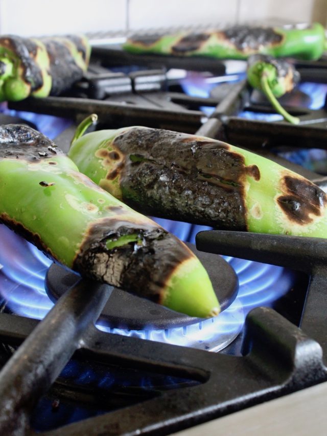 hatch chiles on burners of stove being roasted
