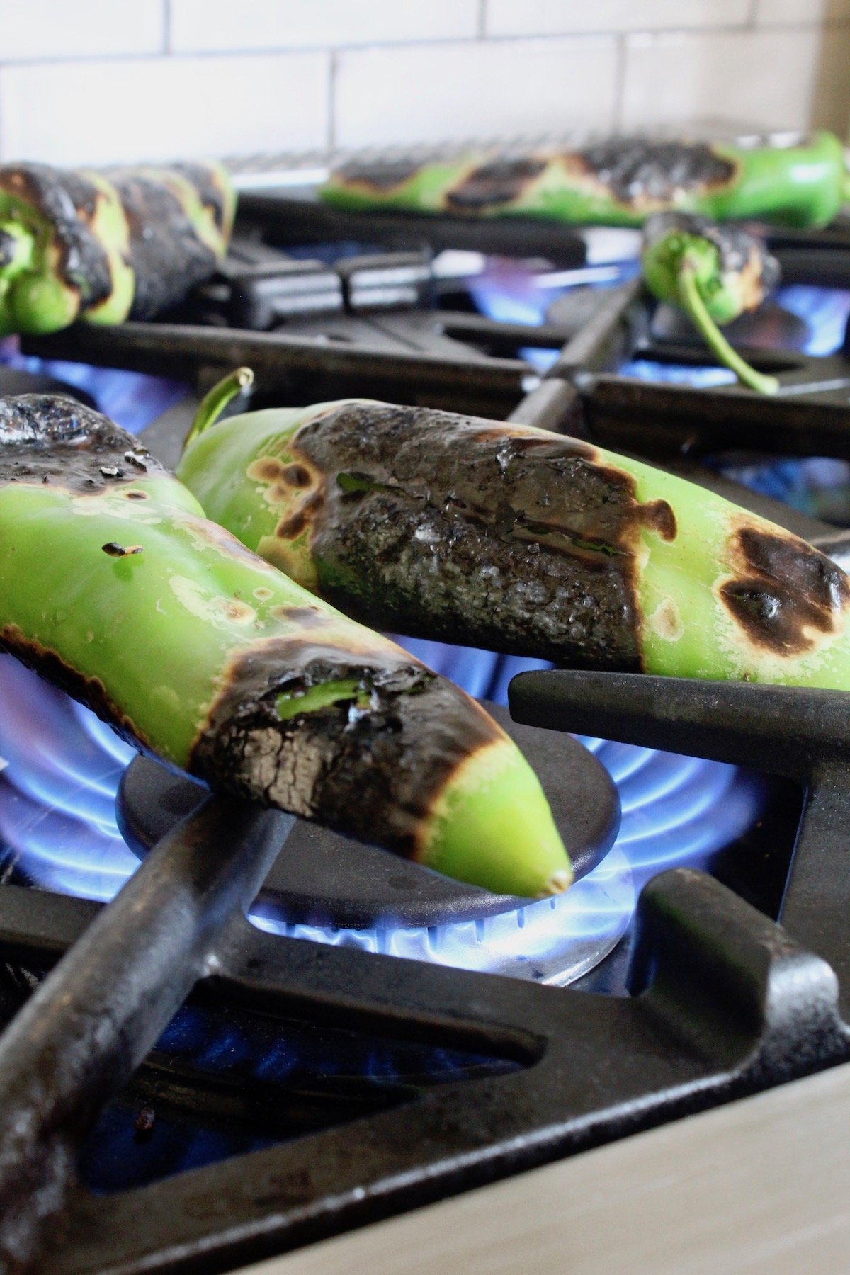 hatch chiles on burners of stove being roasted