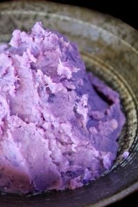 Mashed purple sweet potatoes in a black bowl