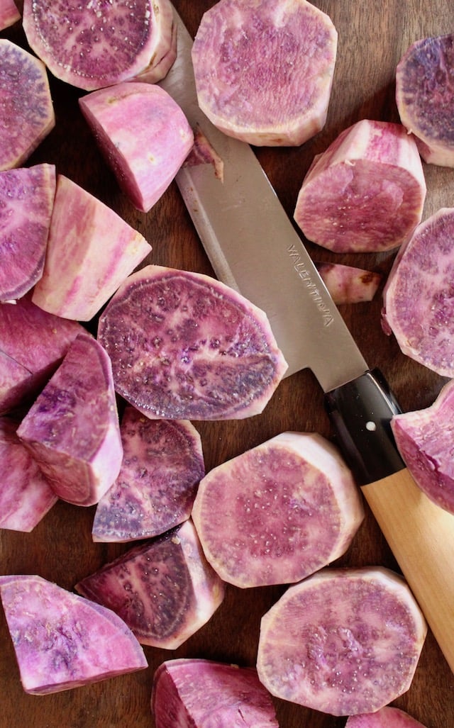 raw hawaiian purple potatoes cut into chunks with knife