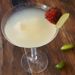 Rambutan martini in a martini glass with a finger lime and rambutan on the rim