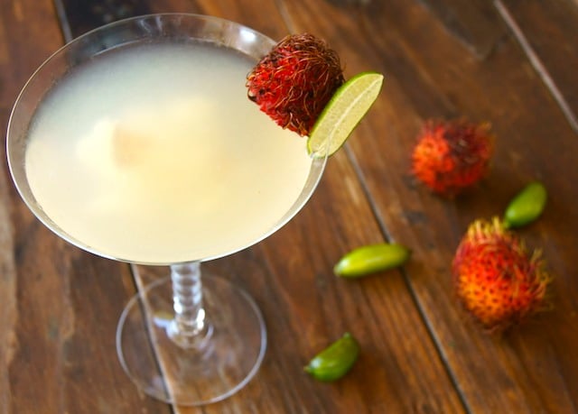 A Rambutan Martini in a martini glass with a martini and finger lime on the rim