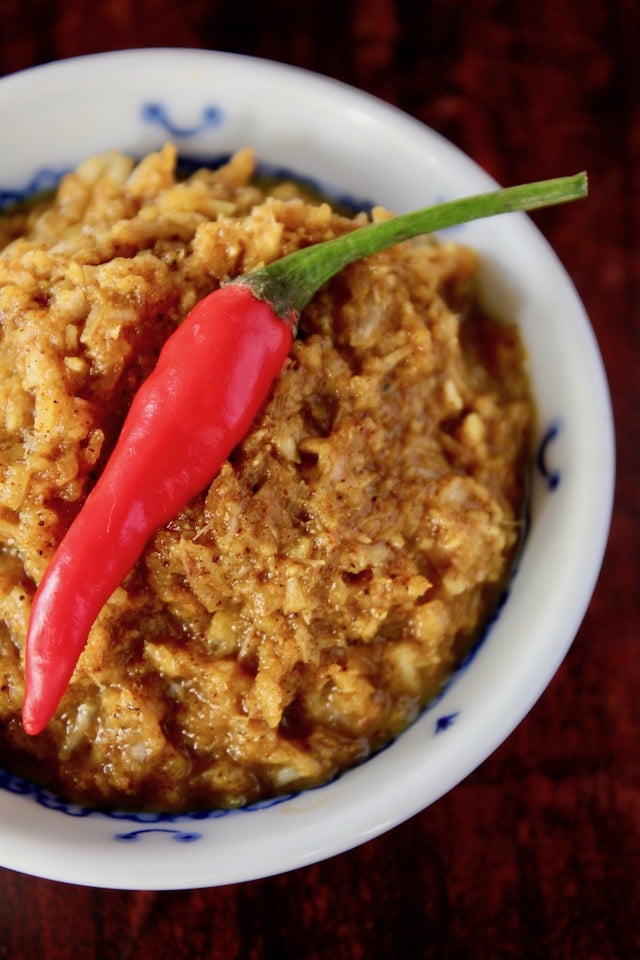 yellow curry paste in a white bowl with tiny red pepper on top