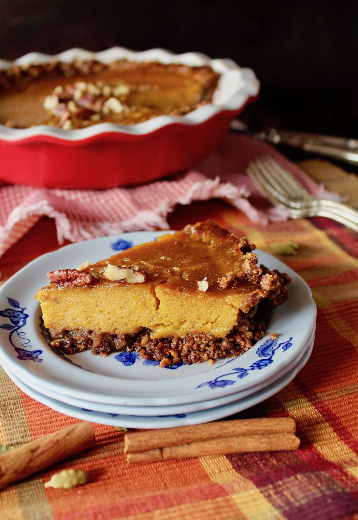 one slice of pecan crusted pumpkin caramel pie on a blue and white plate