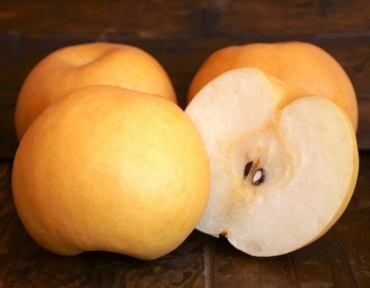 two whole sliced Asian pears, sliced in half of wood background