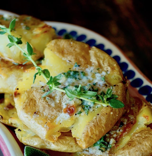 Close up of Herb Garlic Smashed Potatoes with fresh thyme sprig.