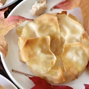 Close up of one pastry-wrapped Asian pear half, surrounded by maple leaves.