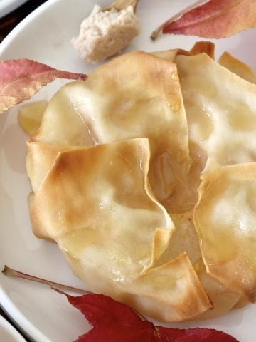 Close up of one pastry-wrapped Asian pear half, surrounded by maple leaves.