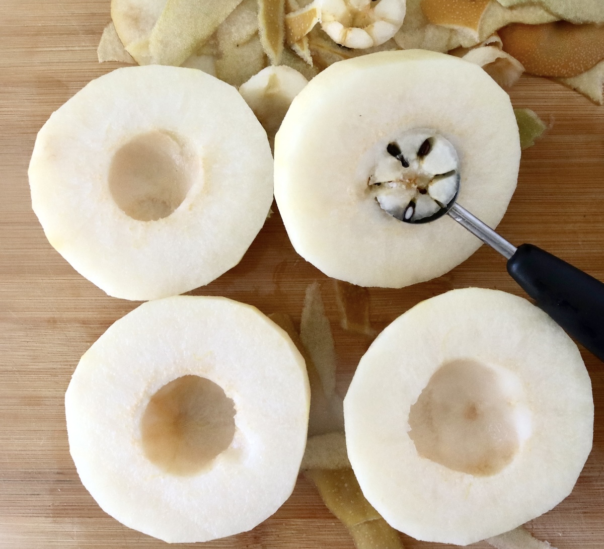 Baked-Asian-Pear-Recipe Four halves of Asian pear with a melon baller scooping out the seeds of one of them.