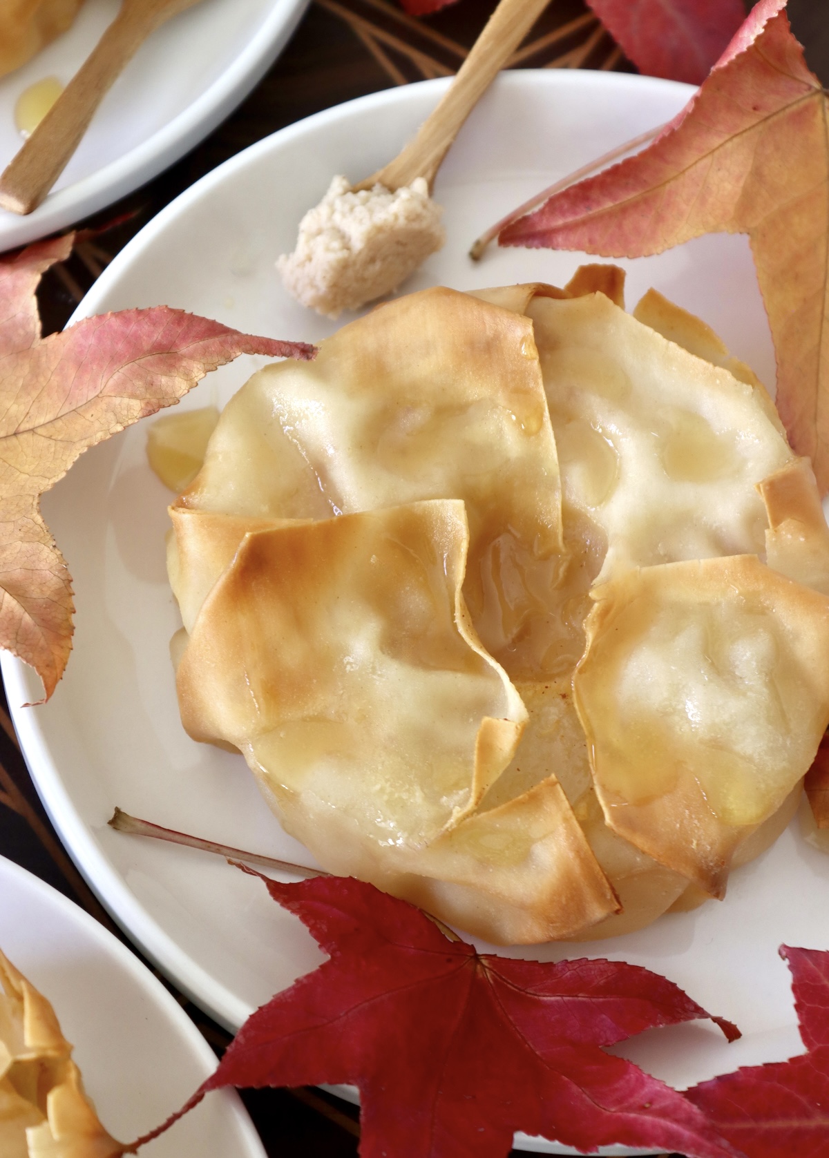 Baked-Asian-Pear-Recipe Close up of one pastry-wrapped Asian pear half, surrounded by maple leaves.