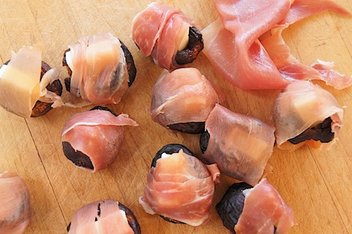 Dried figs with a slit cut into each one, with a small piece of cheese inserted into it, and wrapped in prosciutto.