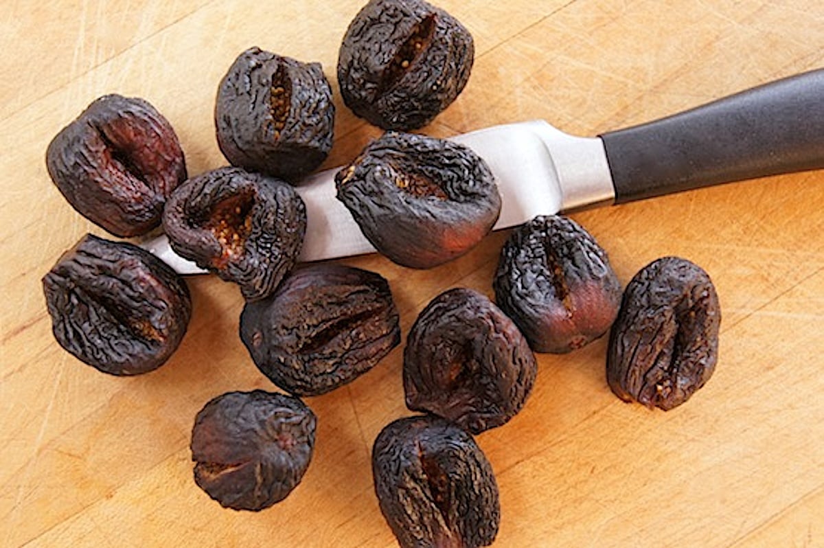 Dried figs with a slit cut into each one, with a paring knife.