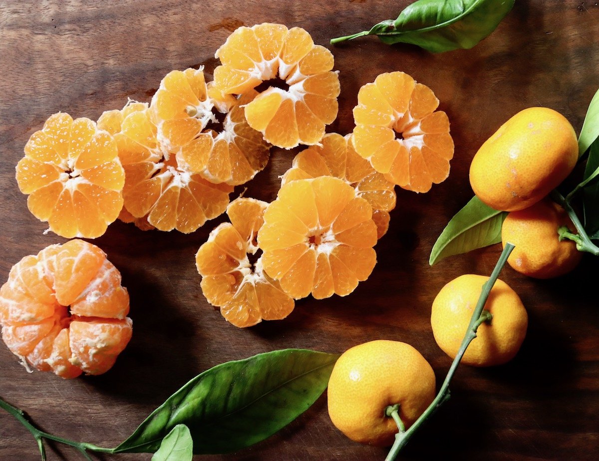 dark wood cutting board with slices of satsumas