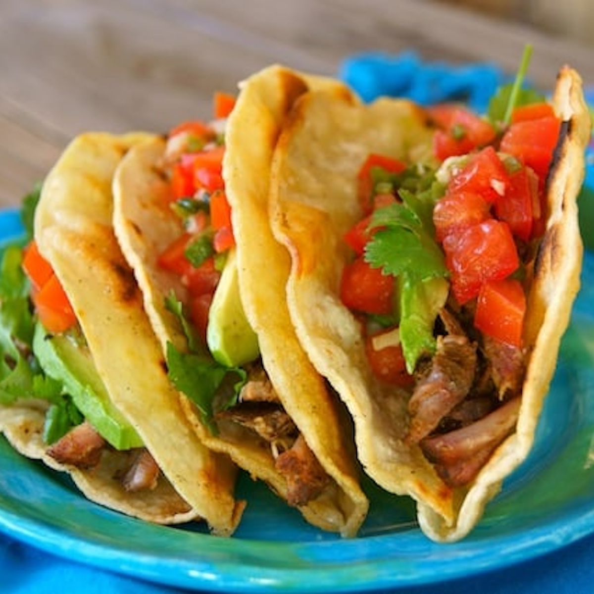 Pickled-Tomato-Pulled-Pork-Tacos Three Pulled Pork Tacos on a turquoise ceramic plate.