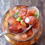 Pickled tomato salsa in a jar with a spoonful on top.