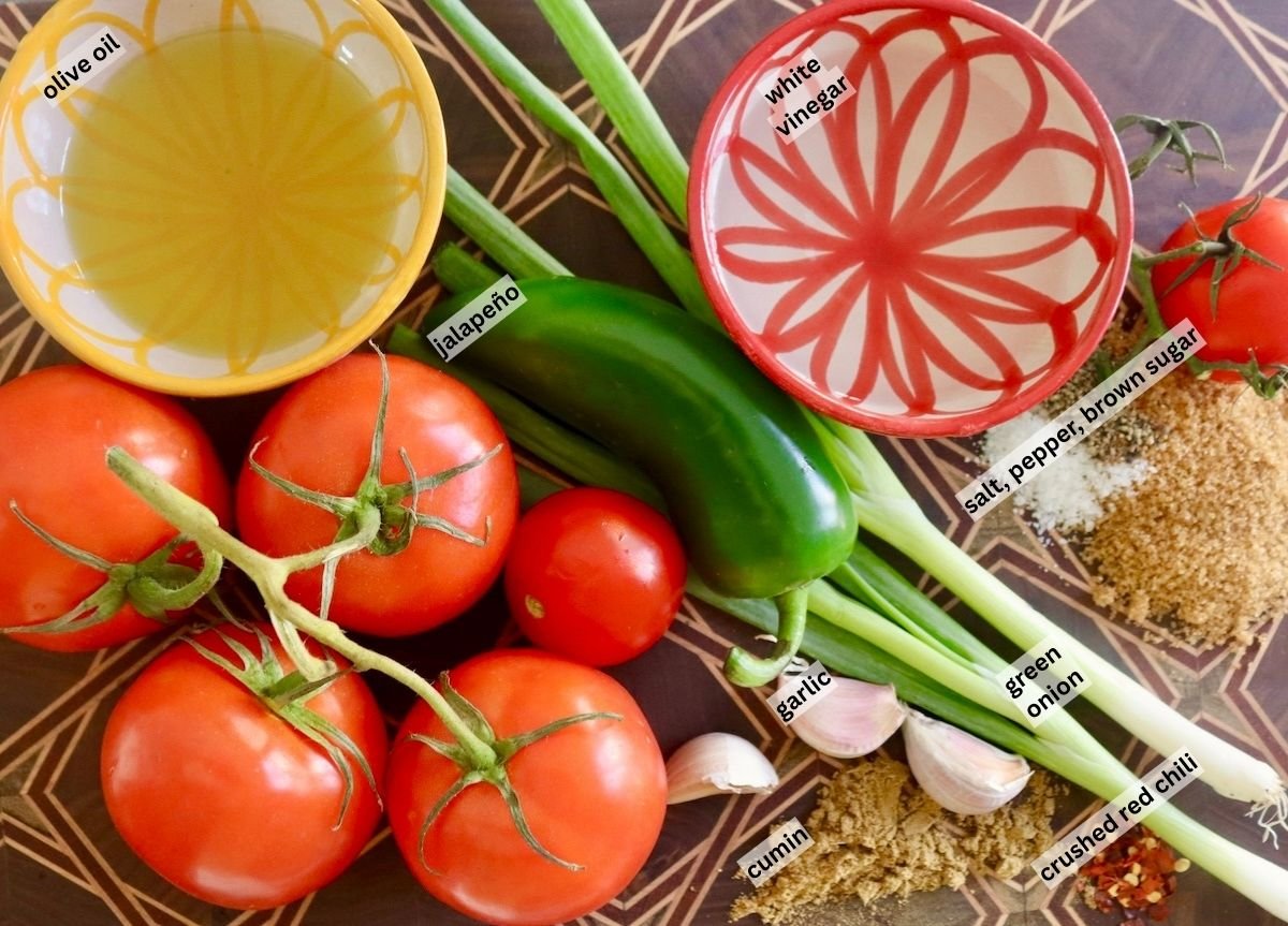 Ingredients for pickled tomatoes salsa including jalapeno, scallions,tomatoes, garlic, cumin, salt, pepper, sugar, vinegar and oilive oil.