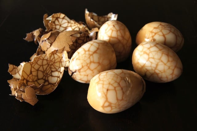 Chinese Marbled Tea Eggs on a black surface with shells in background