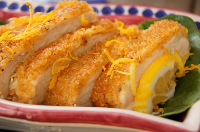 Quinoa Fried Chicken sliced on a platter with lemon