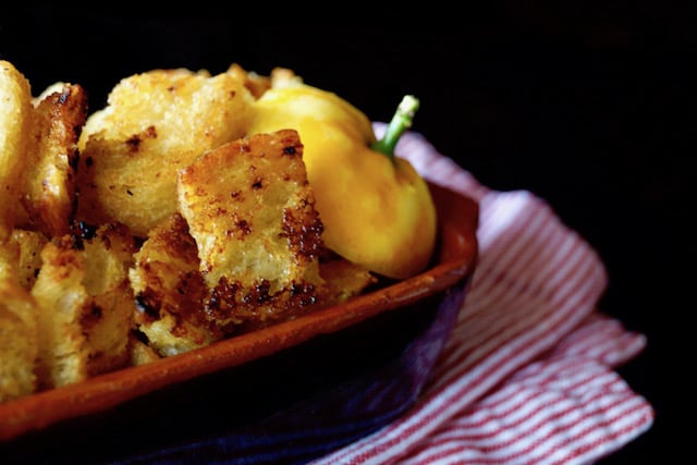 Lemon Garlic Roasted Croutons in a ceramic baking dish with the top of a lemon with stem