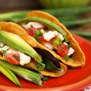 two ceviche tacos with avocado on a red plate