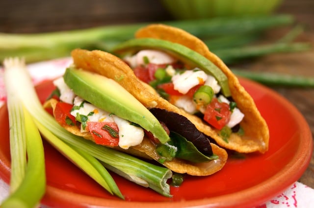 Two Halibut Blood Orange Ceviche Tacos on a red plate with scallions.