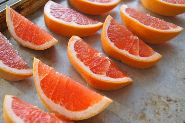 fresh pink-colored grapefruit wedges on a baking sheet